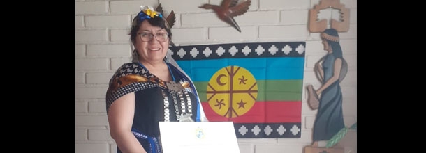 Mujer vestida con tenida mapuche mostrando un diploma